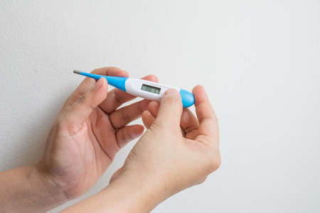Women hands holding a digital thermometerの写真素材
