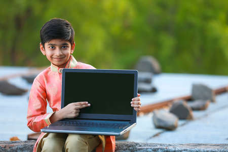 Indian child wearing traditional cloth and showing laptop screen