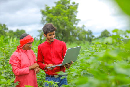 Young Indian farmer with agronomist at Cotton field , showing some information in laptopの写真素材