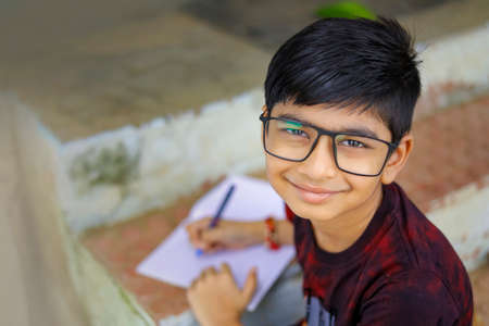 Indian little boy writing on note bookの写真素材