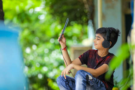 Indian / asian boy listening music or learning on mobile phoneの写真素材