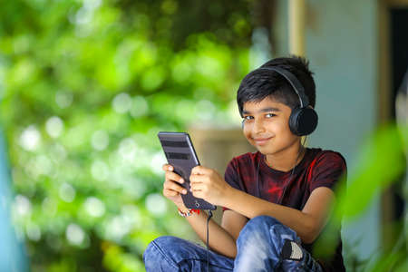 Indian / asian boy listening music or learning on mobile phoneの写真素材