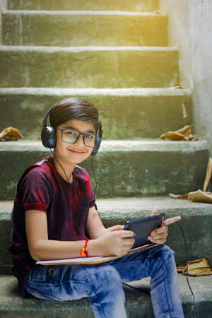 Indian / Asian Little boy studying online using mobile phone at homeの写真素材