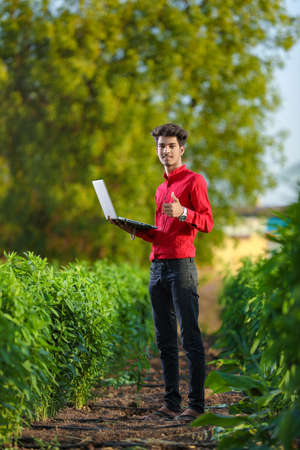 Young indian bank executive standing at field with laptopの写真素材