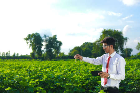 young indian handsome agronomist with test tube and tablet