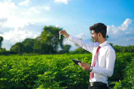 young indian handsome agronomist with test tube and tablet