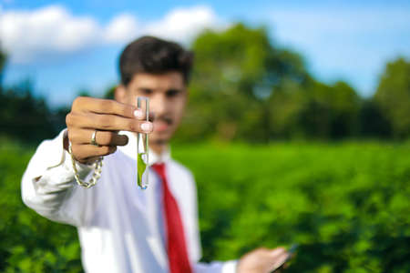 young indian handsome agronomist with test tube and tablet