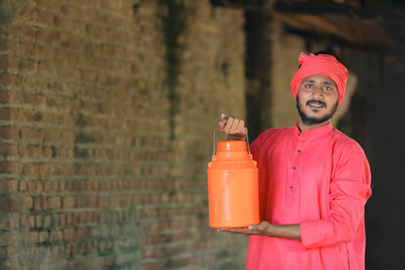 Indian farmer holding milk bottle in hand at dairy farm