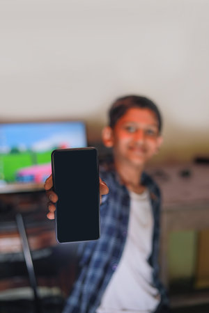 Cute indian little child showing smart phone screen and giving expression