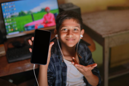 Cute indian little child showing smart phone screen and giving expressionの写真素材