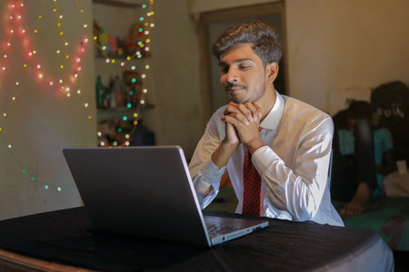 Young indian successful man with laptop at home over lighting backgroundの写真素材