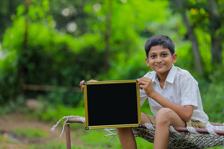Cute indian little child showing chalkboard with copy spaceの写真素材