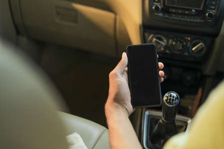 male hand holding mobile phone in car