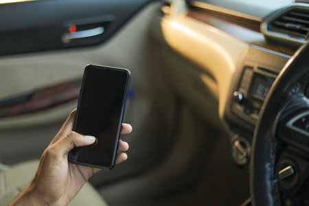 male hand holding mobile phone in car