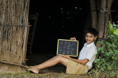 Indian child writing A B C D alphabet on Chalkboardの写真素材