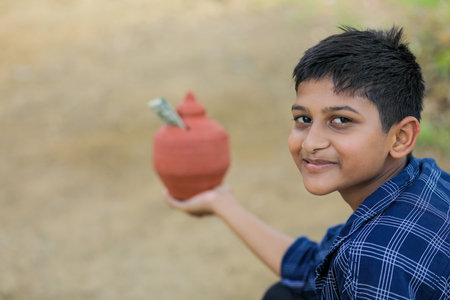 Cute indian child holding clay piggy bank in handの写真素材