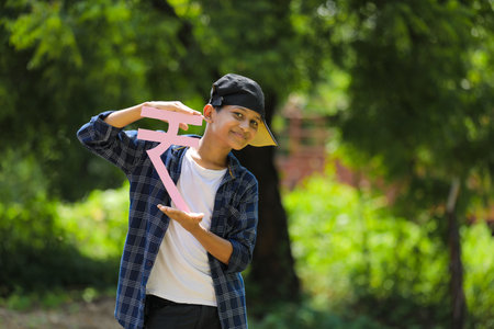 Cute indian little child holding indian rupees symbol in hand and showing expressionの写真素材