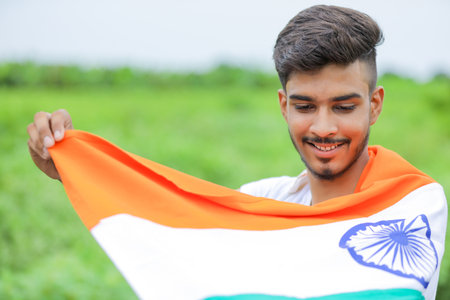 Young indian man waving indian national flag over nature backgroundの写真素材