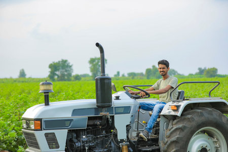Technology and people concept, Portrait of young indian farmer with tractorの写真素材