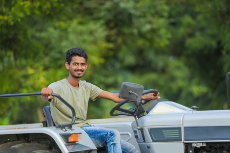 Technology and people concept, Portrait of young indian farmer with tractor