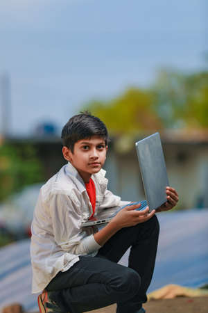 Cute little Indian/Asian boy studying or playing game with laptop computerの写真素材