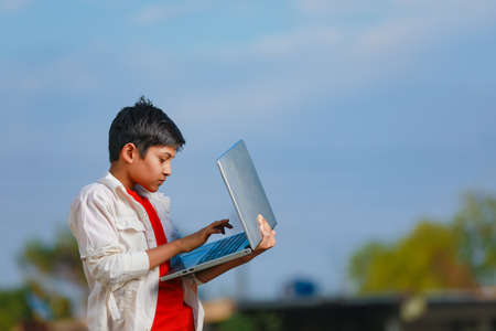 Cute little Indian/Asian boy studying or playing game with laptop computerの写真素材