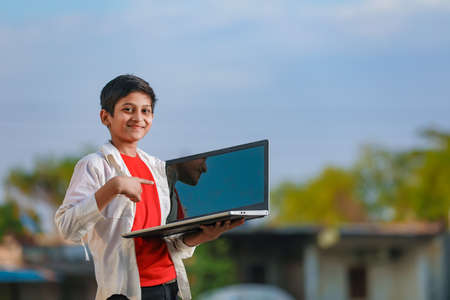 Cute little Indian/Asian boy studying or playing game with laptop computerの写真素材