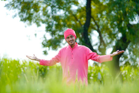 Young indian farmer standing his wheat field and giving happy expressionの写真素材