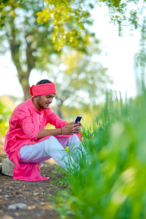 Young indian farmer using smartphone at wheat fieldの写真素材