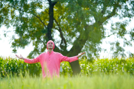 Young indian farmer standing his wheat field and giving happy expressionの写真素材