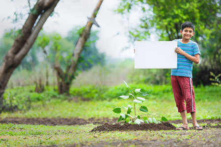 kid planting tree and showing empty boardの写真素材