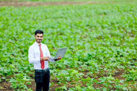 Young indian agronomist using laptop at agriculture fieldの写真素材