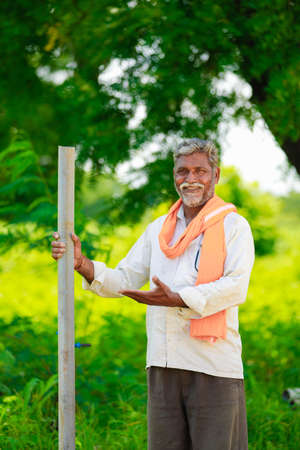 young indian farmer holding pipe at cotton field.の写真素材