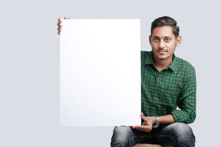 Young Indian man showing blank sing board over white backgroundの写真素材