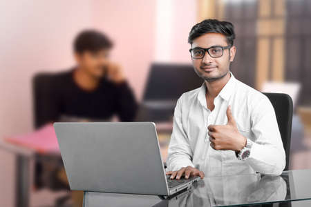 young indian man working at office and showing thumbs upの写真素材