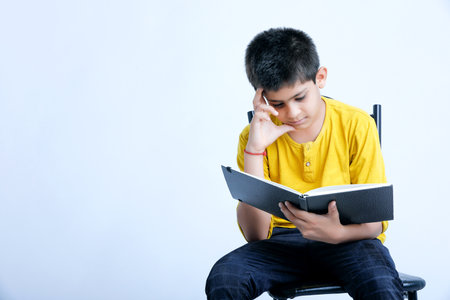 Young indian cute child reading a bookの写真素材