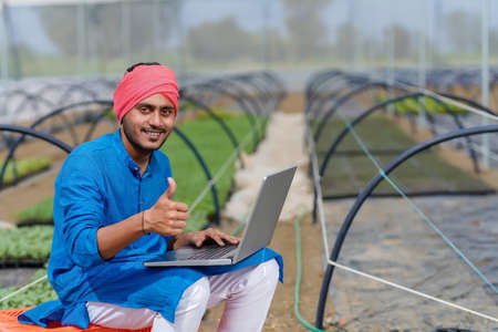 Young indian farmer using laptop at greenhouse or poly houseの写真素材