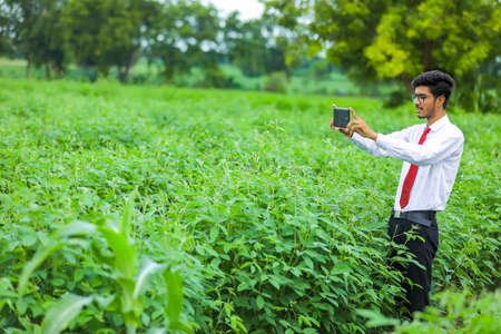 Technology and people concept, Young indian agronomist with tablet at fieldの写真素材