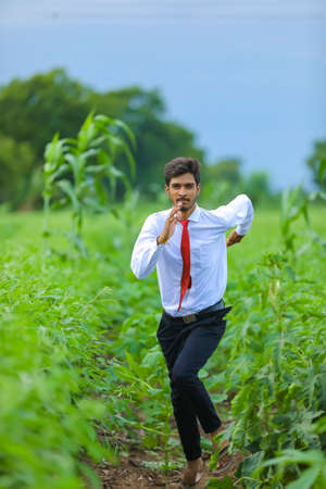 young indian agronomist standing at field and pointing directionの写真素材