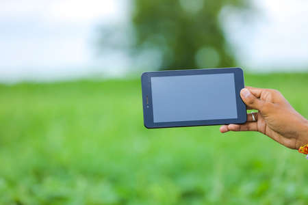 Technology and people concept, Young indian agronomist showing tablet at fieldの写真素材