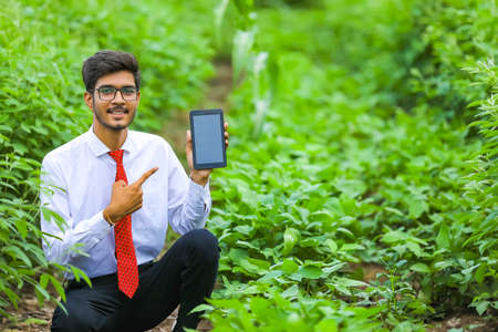 Technology and people concept, Young indian agronomist showing tablet at fieldの写真素材
