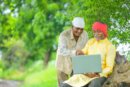 Indian farmer using laptop at field