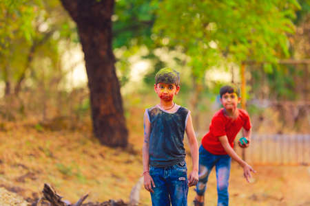 Indian little child throwing color and playing holi colors festival
