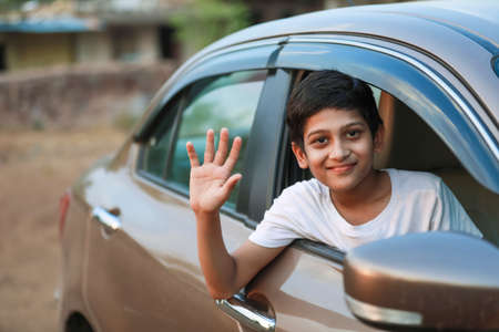 Cute Indian Child waving from car windowの写真素材