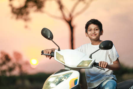 Cute indian little child sitting on scooter and giving multiple expression