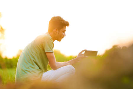Young indian man showing smartphone screen at agriculture field.の写真素材