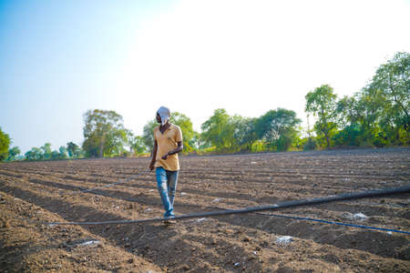 Indian farmer or labour Drip irrigation pipe assemble in agriculture field. rural scene.