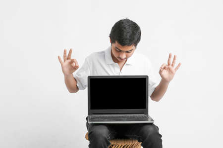 Indian college student showing laptop screen on white background.