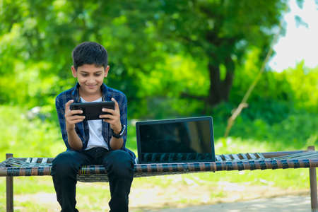 Cute indian schoolboy studying online on tablet at home
