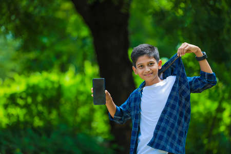 Cute indian schoolboy studying online on tablet at homeの写真素材